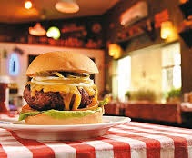 Foto de uma mesa na lanchonete com um hamburgue em cima da mesa